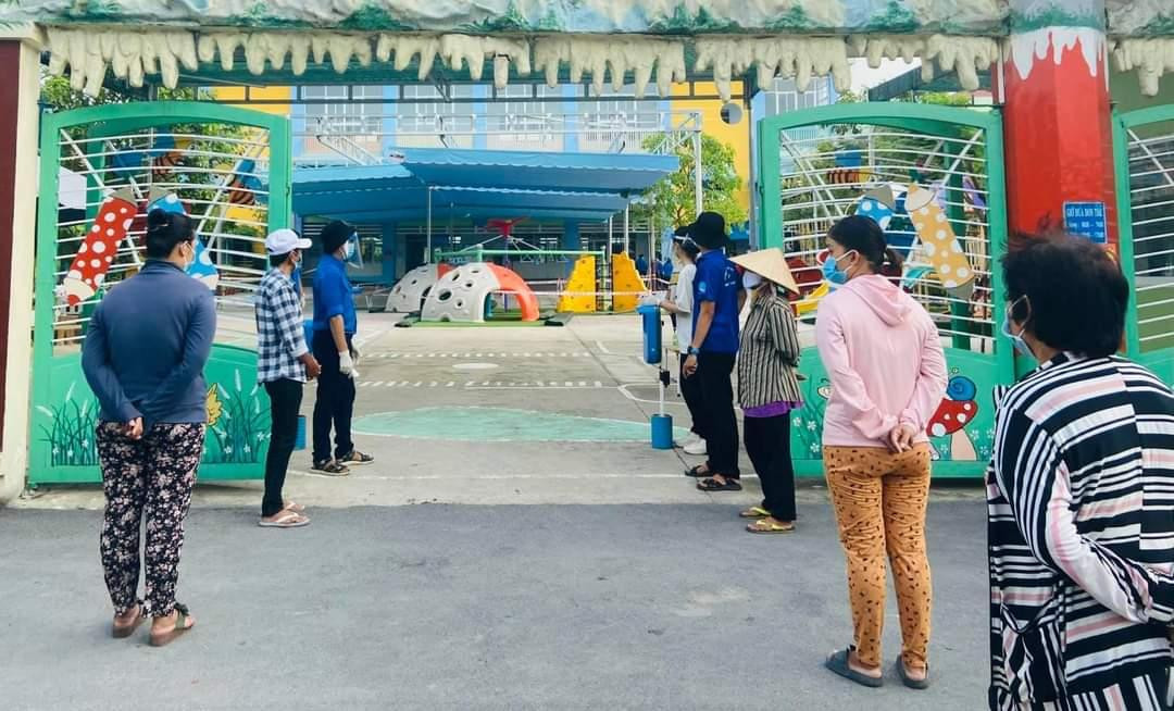 Người dân tuân thủ khoảng cách phòng chống dịch khi đến nhận. (Ảnh: Văn Minh)