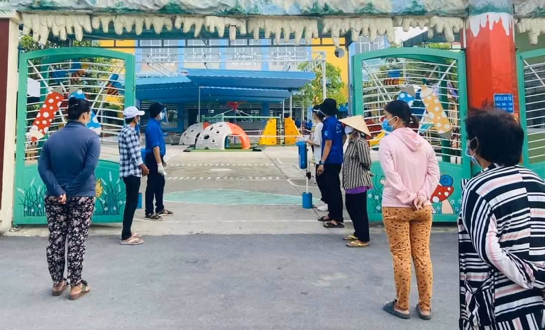 Người dân tuân thủ khoảng cách phòng chống dịch khi đến nhận. (Ảnh: Văn Minh)