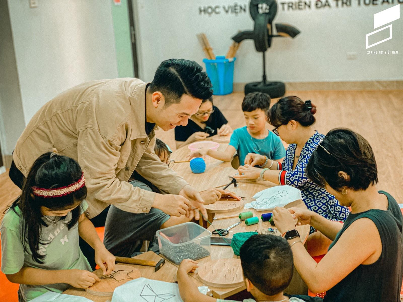 Dũng tận tình hướng dẫn các em nhỏ làm tranh chỉ đinh. Dũng tận tình hướng dẫn các em nhỏ làm tranh chỉ đinh.