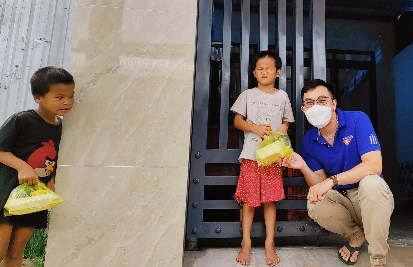 Tình nguyện viên mang cơm đến trao tận nhà cho các em nhỏ có hoàn cảnh khó khăn.