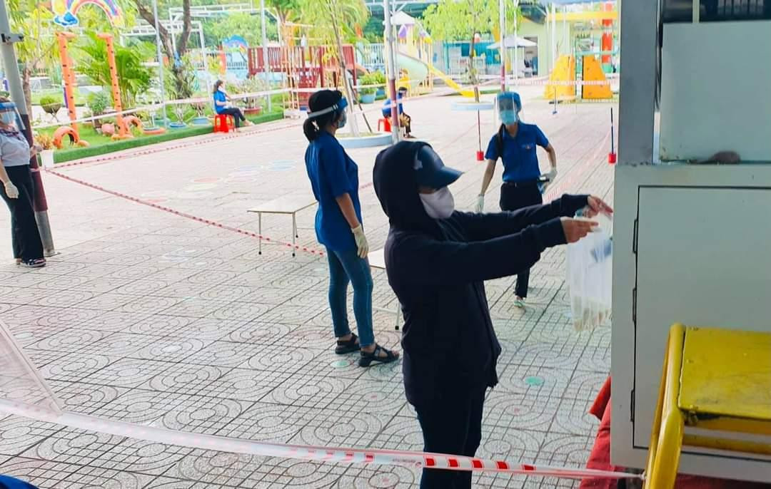 Trong ngày đầu đặt máy người dân xếp hàng theo hướng dẫn của tình nguyện viên vào nhận gạo. (Ảnh: Văn Minh)