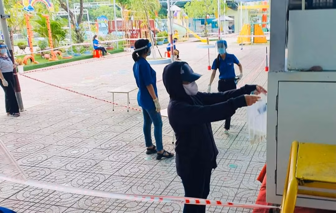 Trong ngày đầu đặt máy người dân xếp hàng theo hướng dẫn của tình nguyện viên vào nhận gạo. (Ảnh: Văn Minh)