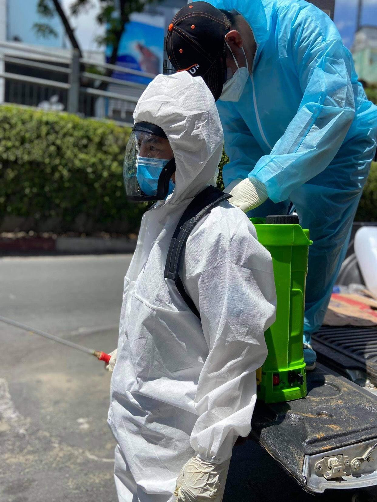 Thanh Tuấn đang được tình nguyện viên trong nhóm hỗ trợ để chuẩn bị cho công việc khử khuẩn.