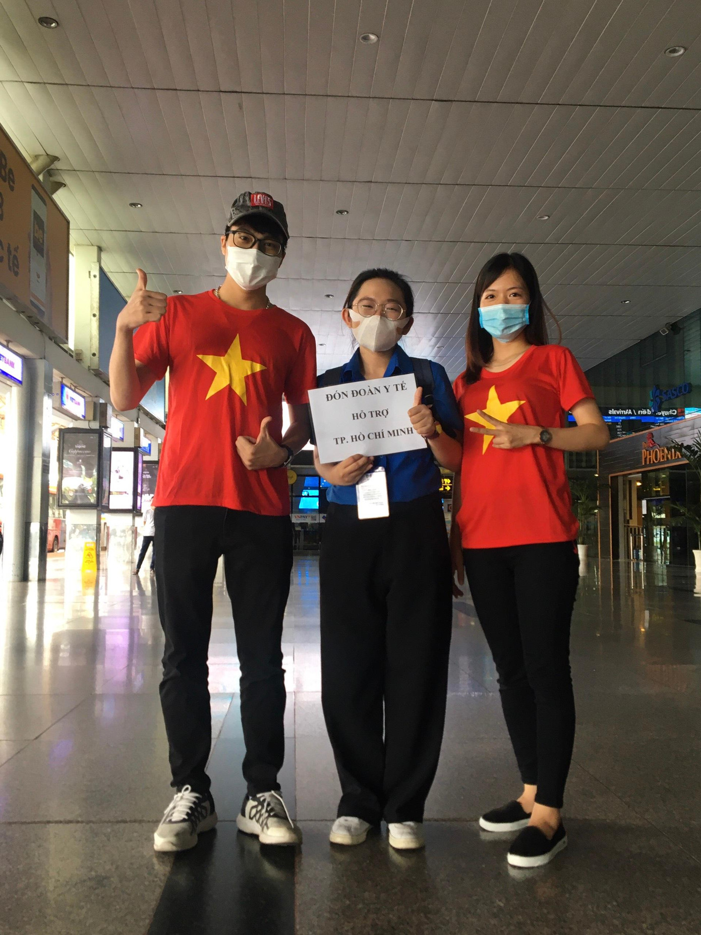 Thy ở giữa cùng hai người bạn tình nguyện viên đón các đoàn tại sân bay Tân Sân Nhất.