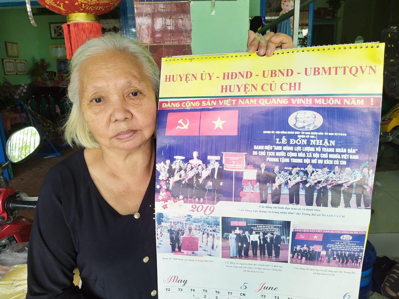 Chị Lê Thị Sương bên những bức ảnh Trung đội nữ du kích Củ Chi nhận danh hiệu Anh hùng Lực lượng vũ trang. (Ảnh: Trần Nguyễn Anh)