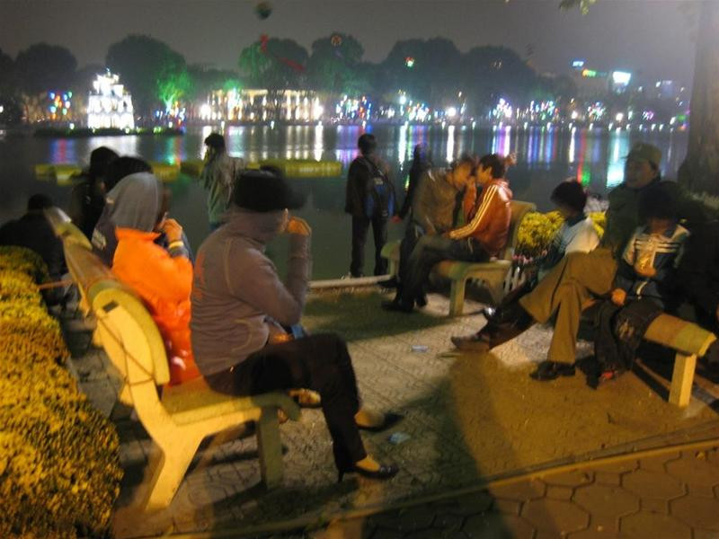 Mưa phùn và trời lạnh buốt song các ghế đá ven Hồ Gươm vẫn không còn một chỗ trống. Ảnh : Văn Việt