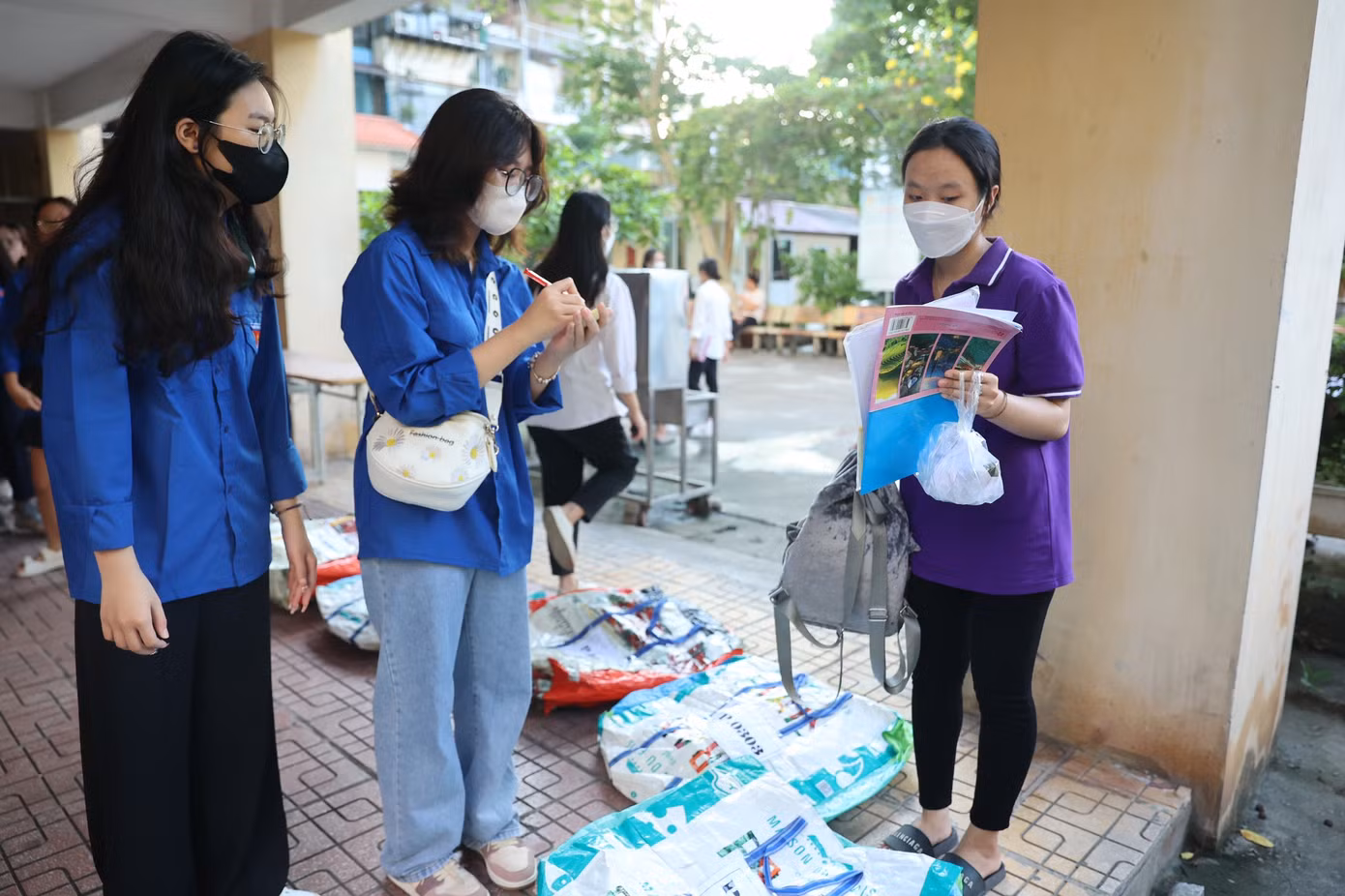 Thanh niên tình nguyện hướng dẫn, nhắc nhở thí sinh gửi hết đồ đạc, đặc biệt điện thoại ở khu vực gửi đồ. Đồ được gửi vào các túi to, sau đó thanh niên tình nguyện sẽ tập kết ở một phòng riêng biệt đảm bảo cách xa phòng thi. (Ảnh: Như Ý).