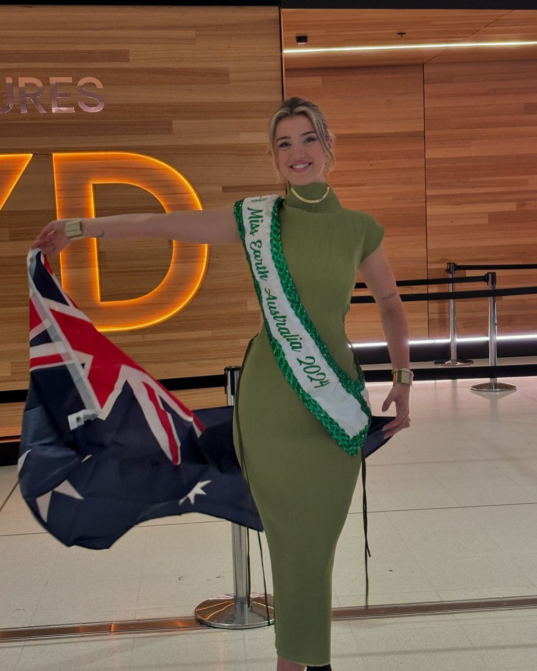 Đại diện Australia - Jessica Lane mặc váy xanh bó sát khi ra sân bay đi thi Miss Earth. Người đẹp đang theo học cử nhân báo chí, chuyên ngành viết sáng tạo và xuất bản. Cô muốn tận dụng kiến thức về lĩnh vực kể chuyện để thúc đẩy các sáng kiến xanh và những thay đổi tích cực về môi trường. Ngoài ra, cô còn ủng hộ phúc lợi động vật biển tại quê hương mình.