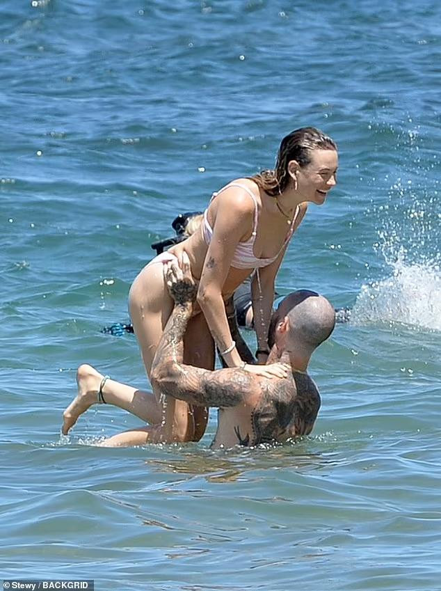 Kết hôn được 7 năm, cặp đôi vẫn ngọt ngào như thuở ban đầu. Paparazzi chụp được khoảnh khắc thủ lĩnh ban nhạc Maroon 5 bế bổng bà xã siêu mẫu lên cao trước khi ném cô trở lại biển.