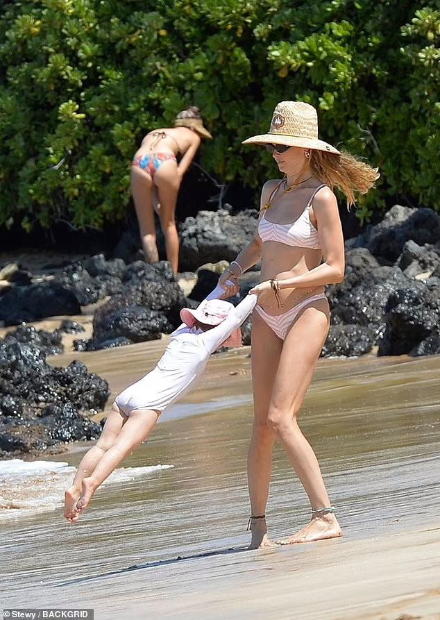 Trong khi đó, thiên thần nội y gốc Namibia xoay vòng con gái nhỏ trên bãi biển.