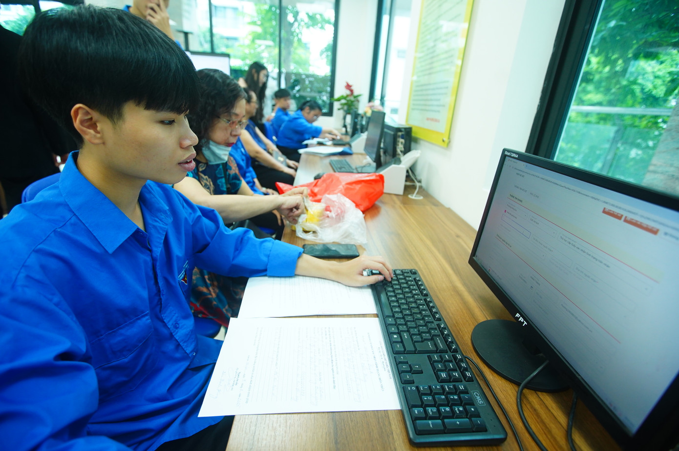 Tình nguyện viên &quot;trực chiến&quot; bên khu vực máy tính, giúp người dân kê khai online, nhập dữ liệu nhanh chóng.