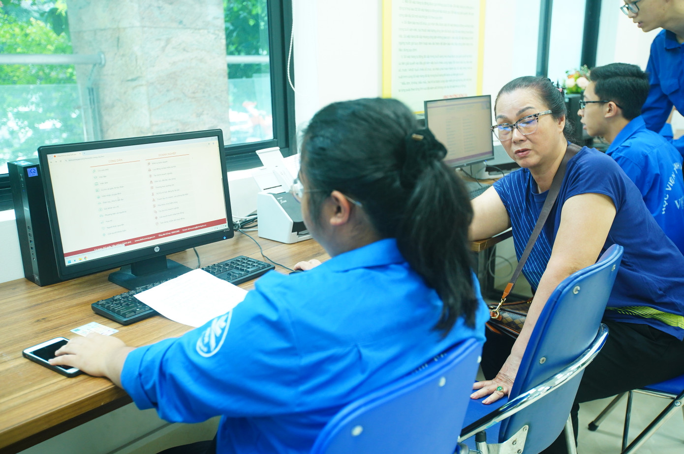 Tình nguyện viên &quot;trực chiến&quot; bên khu vực máy tính, giúp người dân kê khai online, nhập dữ liệu nhanh chóng.