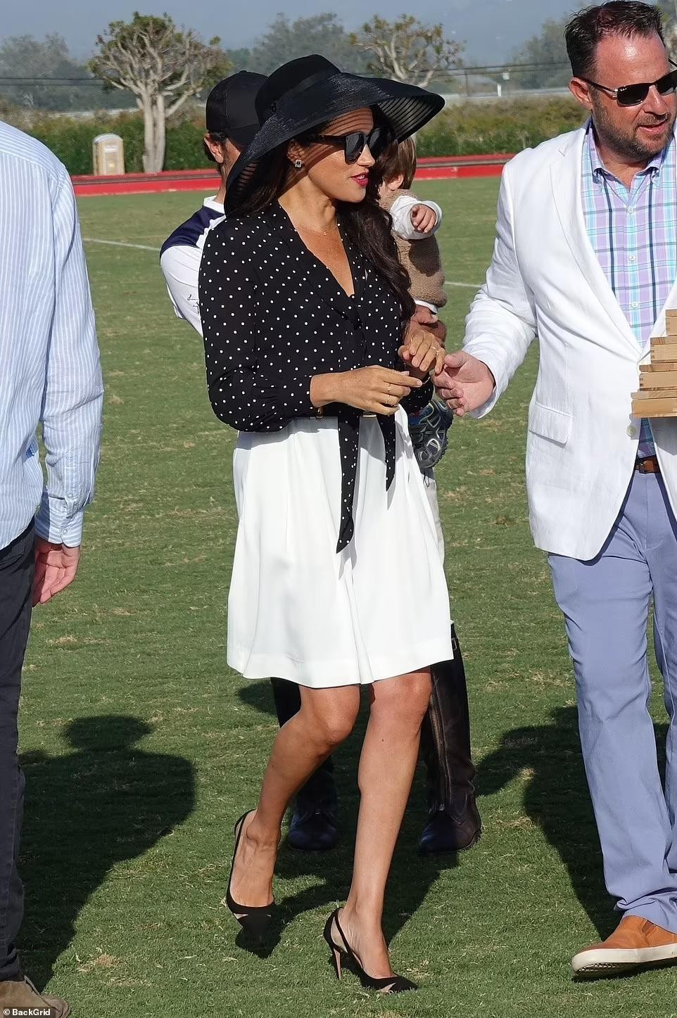 Cựu diễn viên 40 tuổi xuất hiện thanh lịch, dịu dàng với chiếc mũ rộng vành màu đen, áo sơ mi chấm bi đen trắng và quần đùi xếp ly (giá 670 bảng Anh ~ hơn 19 triệu đồng) và giày cao gót đen. Theo Daily Mail, vẻ ngoài của Meghan lấy cảm hứng từ bộ phim &quot;My Fair Lady&quot; (1964) do minh tinh huyền thoại Audrey Hepburn đóng chính.