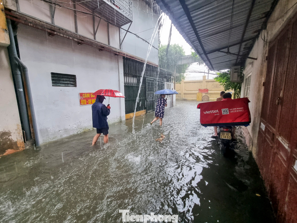 Người dân bì bõm lội nước, nhiều gia đình phải di chuyển xe máy đi gửi chỗ cao hơn.