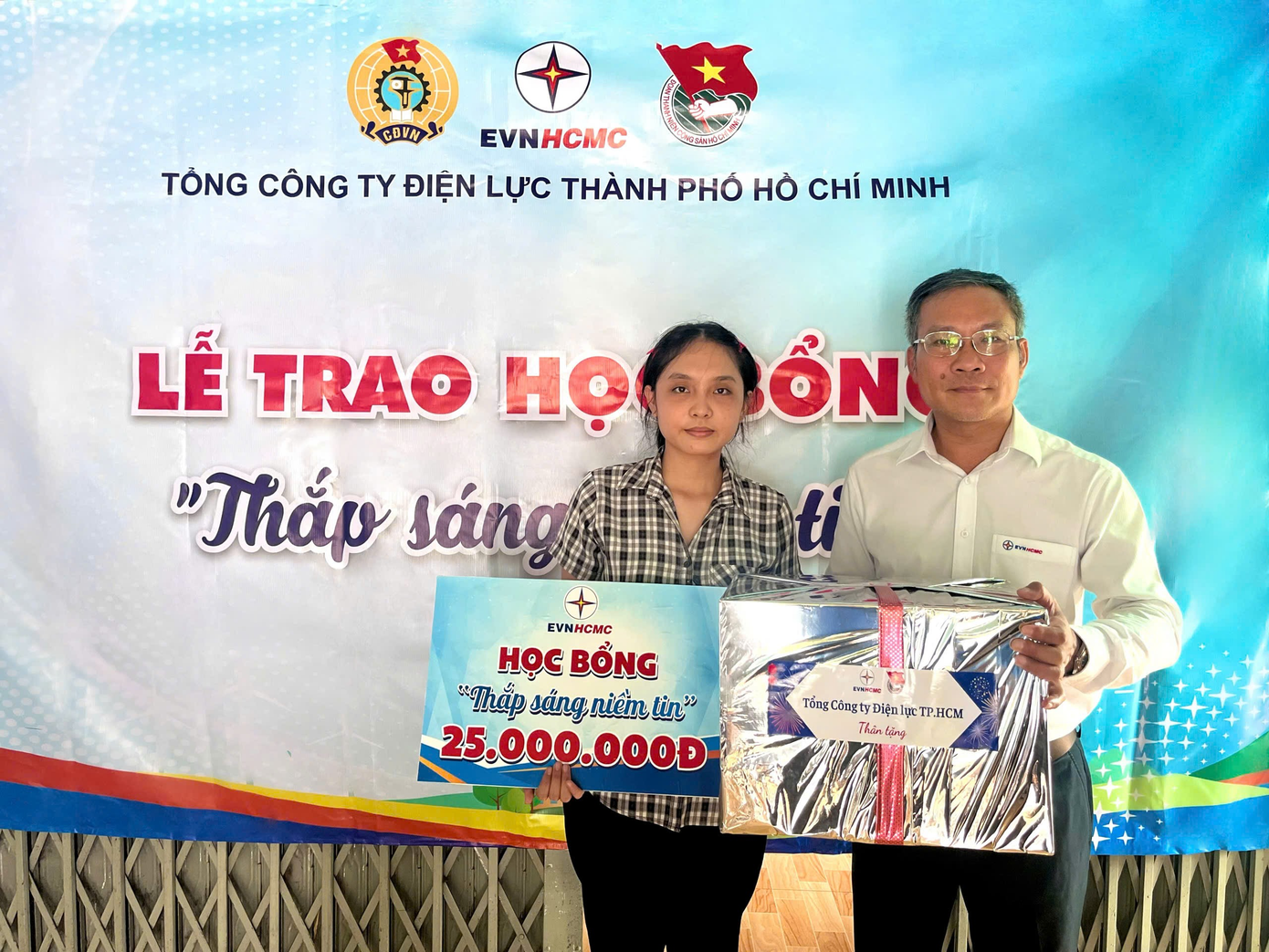 Ông Bùi Trung Kiên – Phó tổng giám đốc EVNHCMC (phải) trao học bổng Thắp sáng niềm tin cho học sinh nghèo.