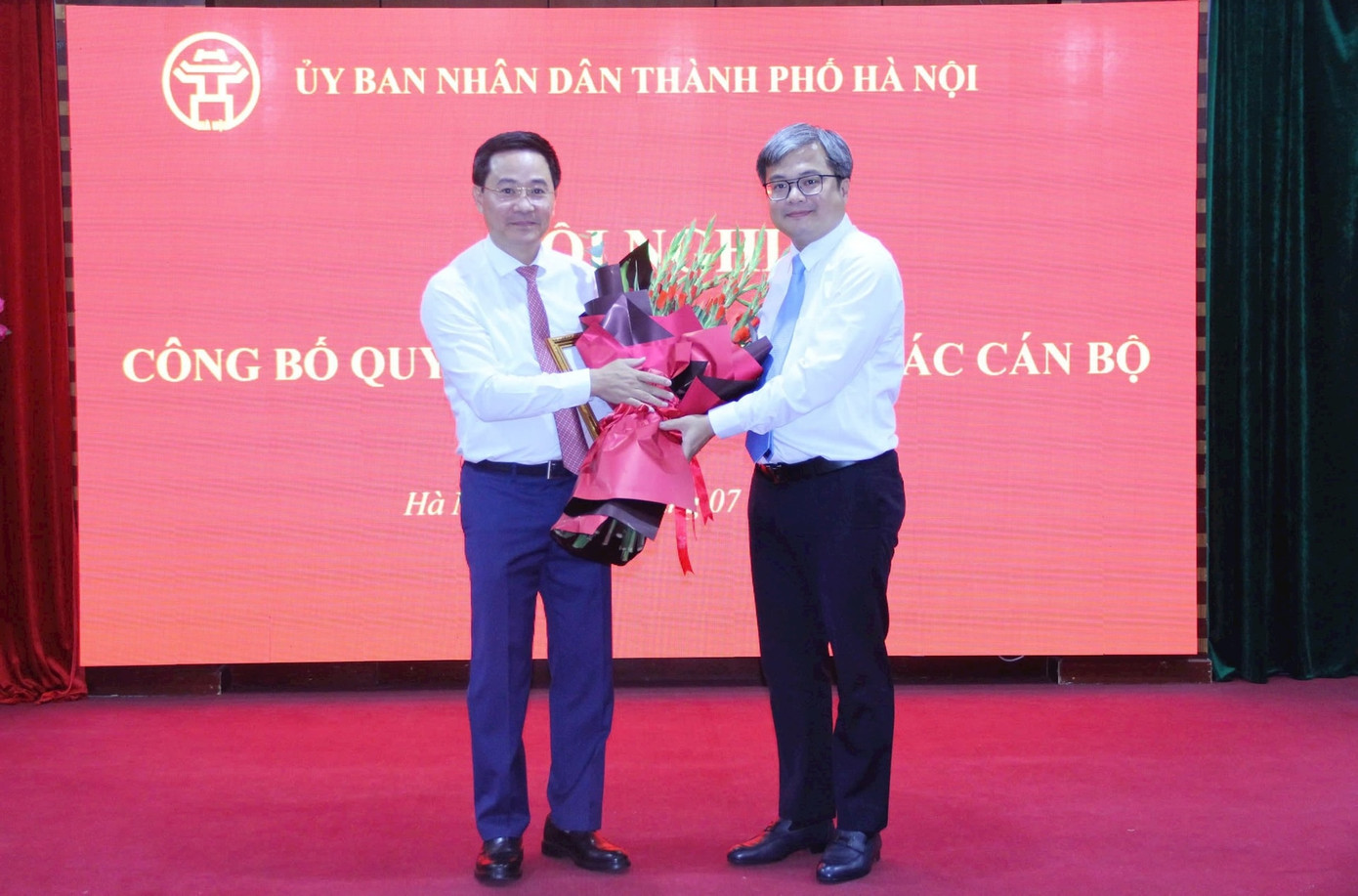 Phó Chủ tịch UBND TP. Hà Nội Trương Việt Dũng (bên phải) trao quyết định và tặng hoa chúc mừng ông Trần Anh Tuấn.