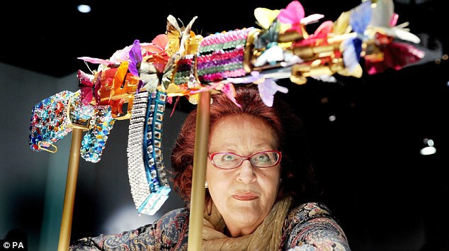 Một nữ nghệ sĩ đang ngồi ngắm khẩu AK-47 được trang trí rất sặc sỡ này