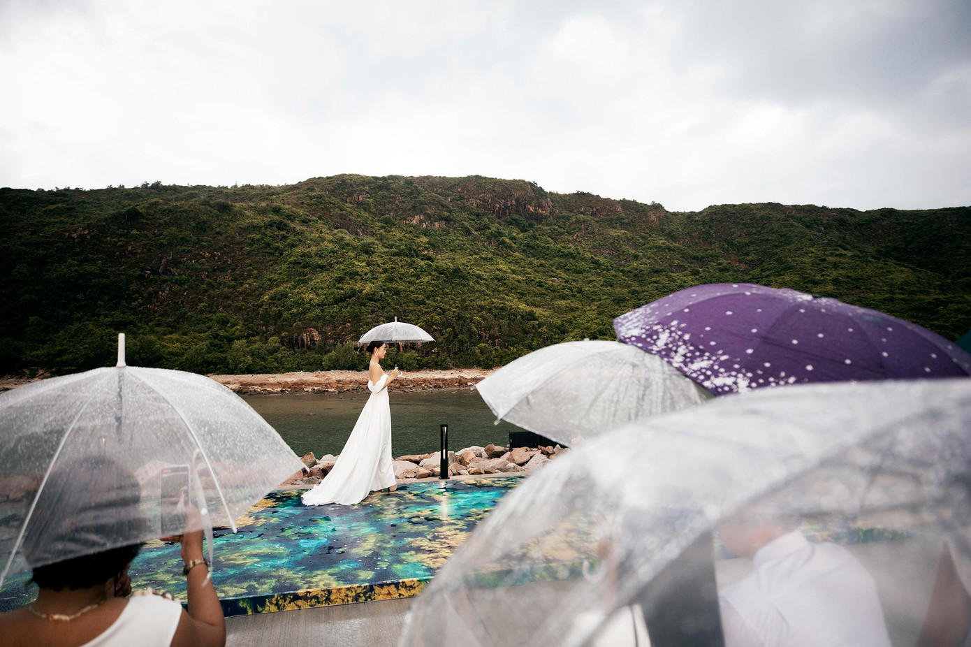 Các thí sinh Miss World Vietnam 2022 trình diễn váy cưới dưới mưa.