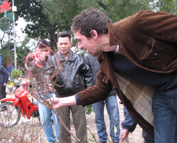 ... và cầm cành đào trị giá khoảng 3 đô la Mỹ lên xem thử, vẻ mặt đầy bất ngờ. 