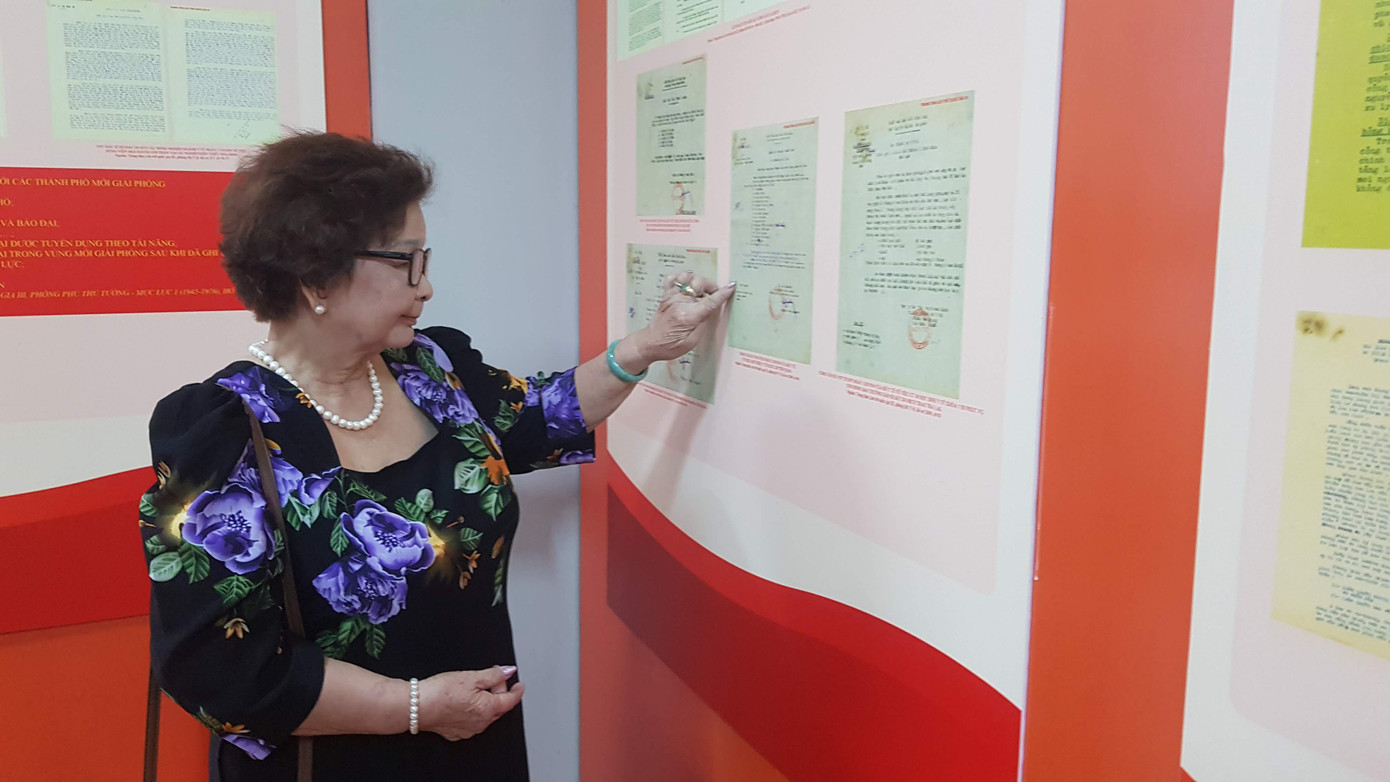 Một phụ nữ từng chứng kiến ngày giải phóng Thủ đô xem những thông tin tại Triển lãm Hà Nội - Ký ức những ngày tiếp quản. Ảnh: Kiến Nghĩa.