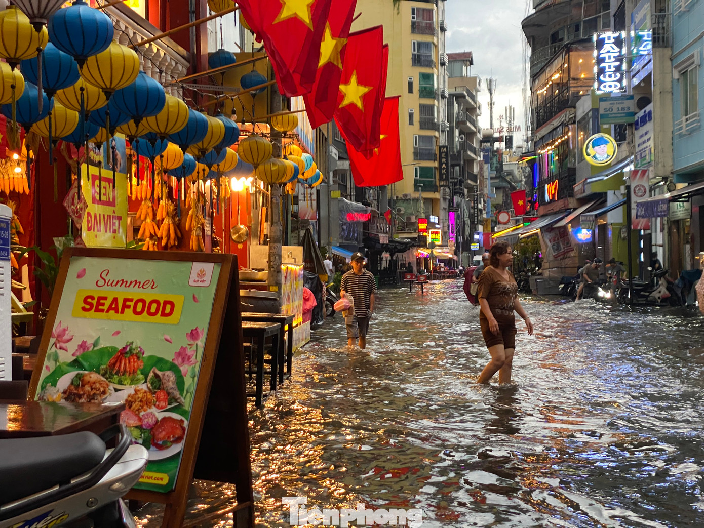 Người dân lội bì bõm trong nước để đi qua phố Bùi Viện.