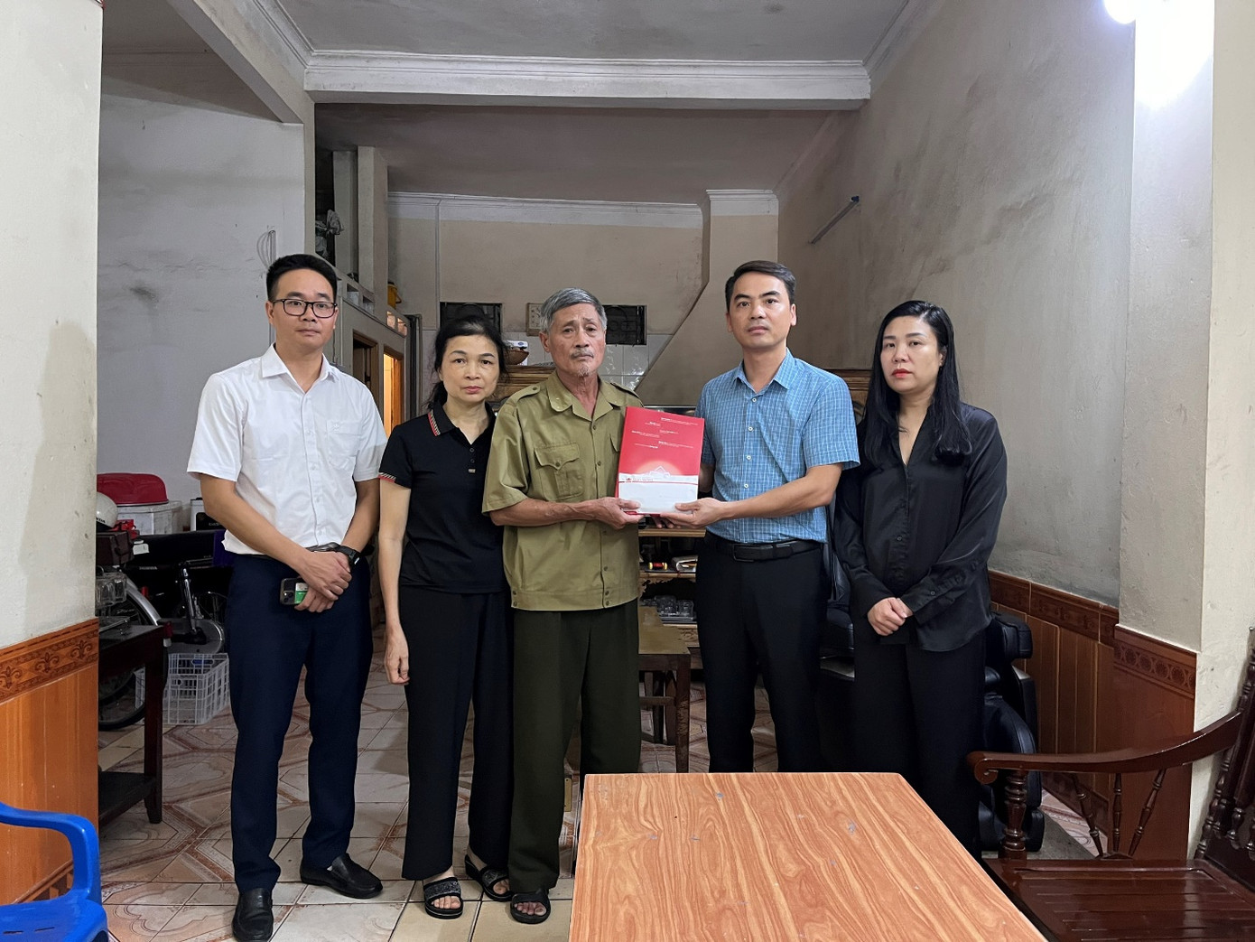 Ông Vũ Hải Lâm (áo xanh) - Phó Tổng Giám đốc Bảo Minh và Bà Phạm Việt Hà (áo đen) – Giám đốc Quản Lý Bảo hiểm tại Đơn vị nơi nạn nhân công tác đã đại diện để trao tiền bồi thường cho gia đình nạn nhân vụ cháy (Ảnh: Bảo Minh).