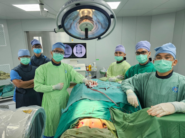 Bệnh nhân trên bàn mổ đang được BS xác định vị trí đường vào để đặt vít dưới máy C-Arm