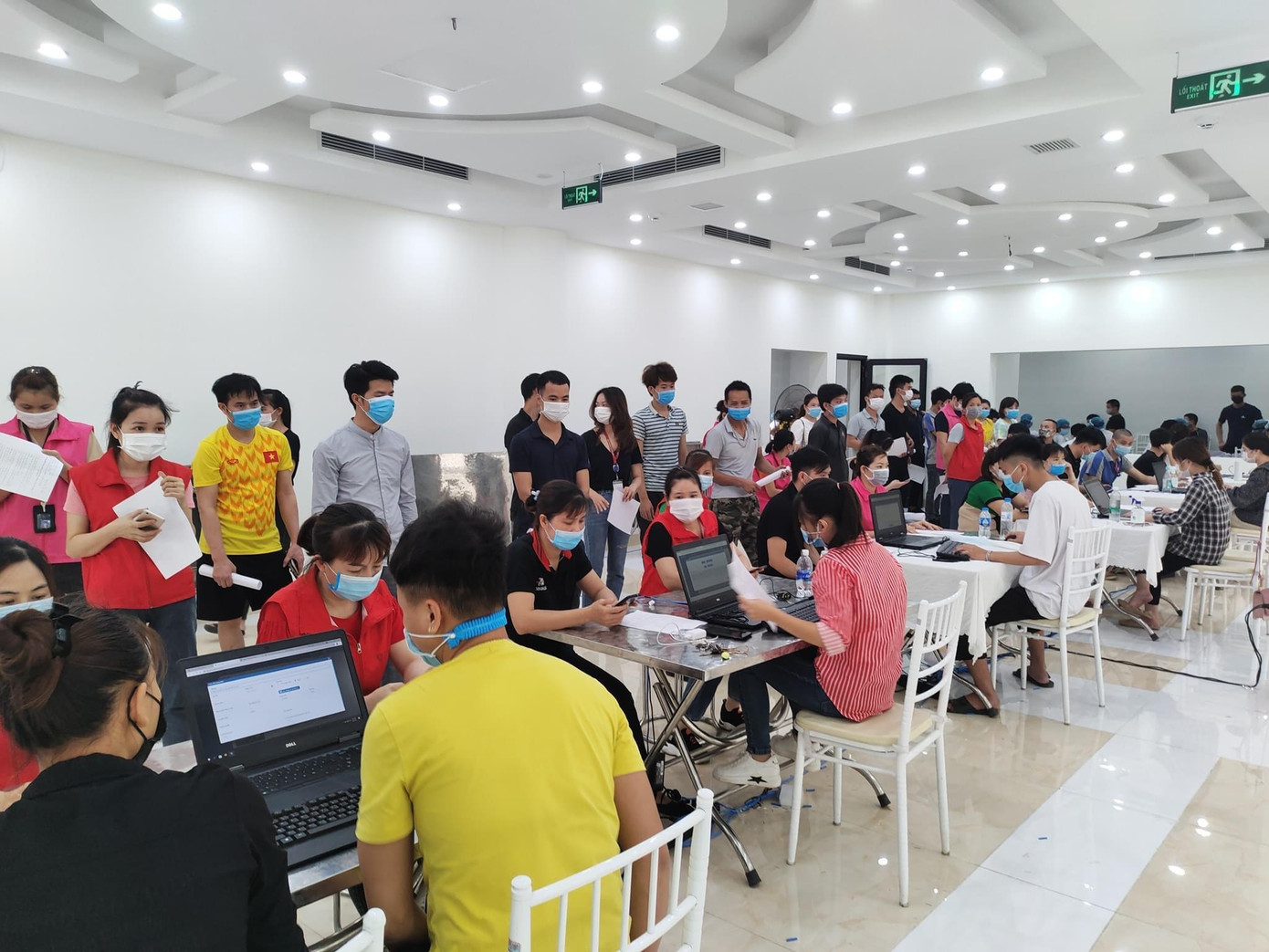 Các tình nguyện viên phối hợp với nhân viên y tế hướng dẫn phân luồng cho công nhân, đo thân nhiệt, huyết áp