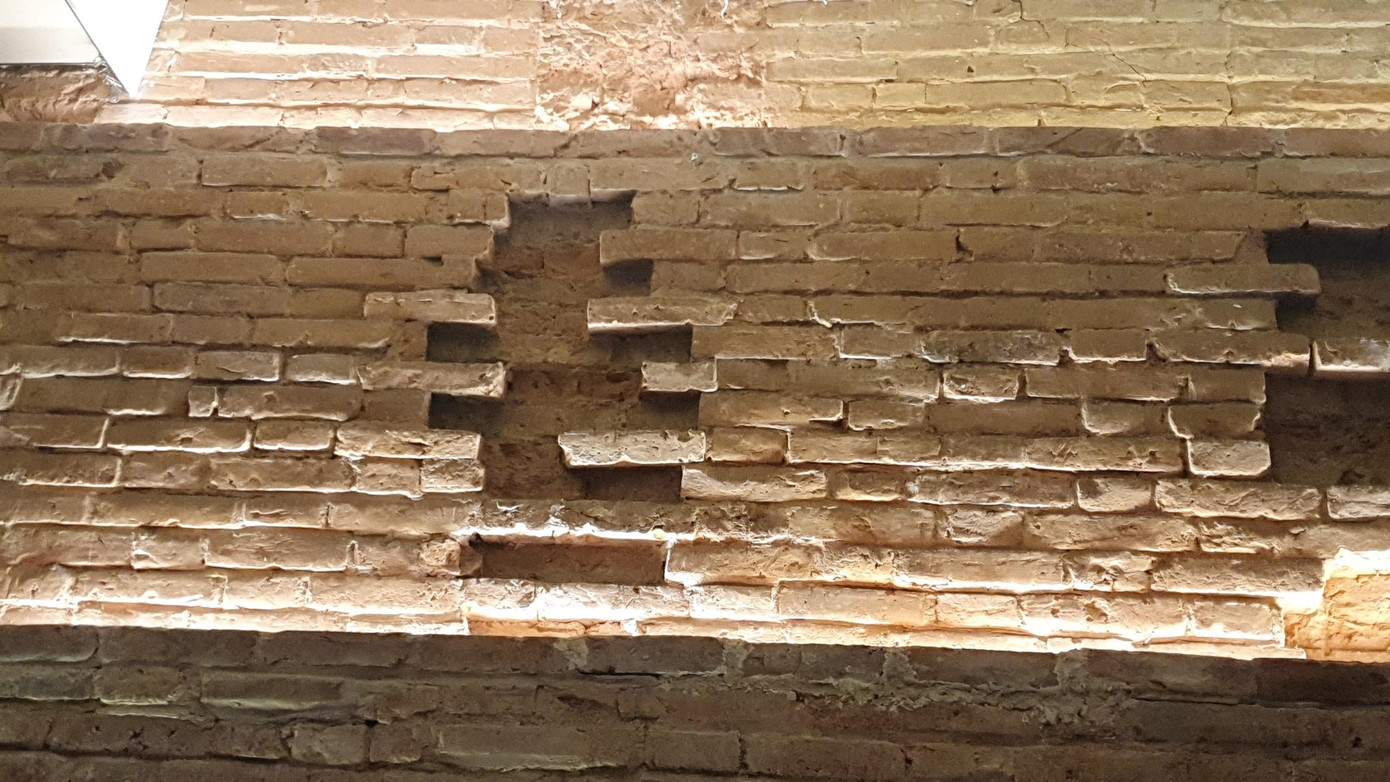 Tại phòng chính giữa tầng hầm, một số vị trí trên cao của tường bị rỗ, gạch bong tróc hoặc rơi ra tạo thành các vết hõm vào tường.