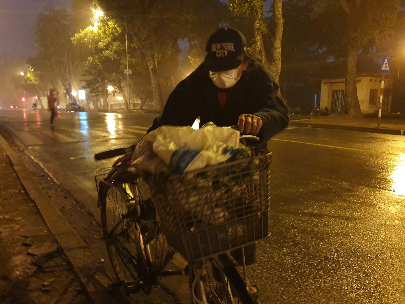 Phía đối diện hồ Thuyền Quang là Cổng công viên Thống nhất. Điểm chờ xe buýt tại đây là nơi cụ Nguyễn Đình Thường, 70 tuổi, quê Hà Giang làm "phòng ngủ” mỗi khi đêm về. Cụ Thường xuống Hà Nội đã 3 năm nay và chưa một lần về thăm nhà. Không có việc làm, kèm dịch bệnh hoành hành nên cụ thường “mưu sinh” bằng việc đi nhặt rác. Gia tài của cụ là một chiếc xe đạp đã cũ và vài bộ quần áo đã sờn rách. Hàng ngày, cụ dắt chiếc xe đi khắp các con phố để nhặt phế liệu.