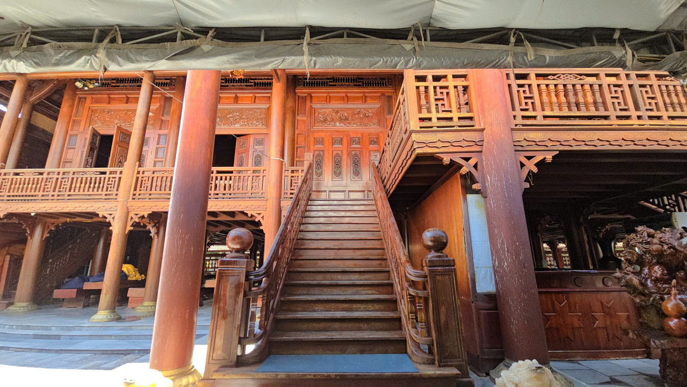 Nhà sàn có lan can bao quanh mặt trước và mặt sau, 15 bậc cầu thang lên xuống của 2 cửa chính.