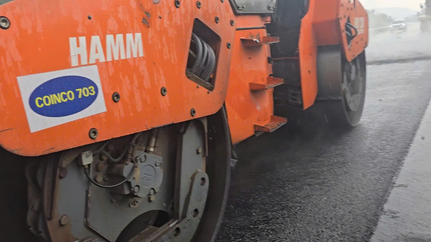 Trên phương tiện và đồng phục của công nhân thi công thảm nhựa dưới trời mưa tại đây ghi là Công ty CP Đầu tư và Xây dựng 703 (COINCO 703), có trụ sở tại Hà Đông, Hà Nội.