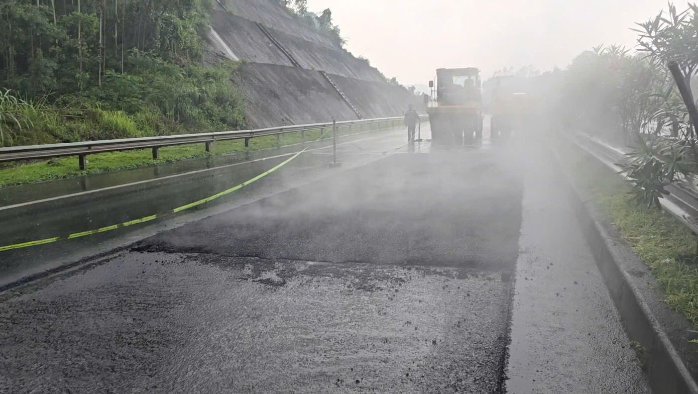 Thấy phóng viên ghi hình, công nhân lập tức ngừng làm việc. Nhưng một lúc sau, khi mưa nhỏ hơn, công nhân và xe lu lại tiếp tục làm việc.