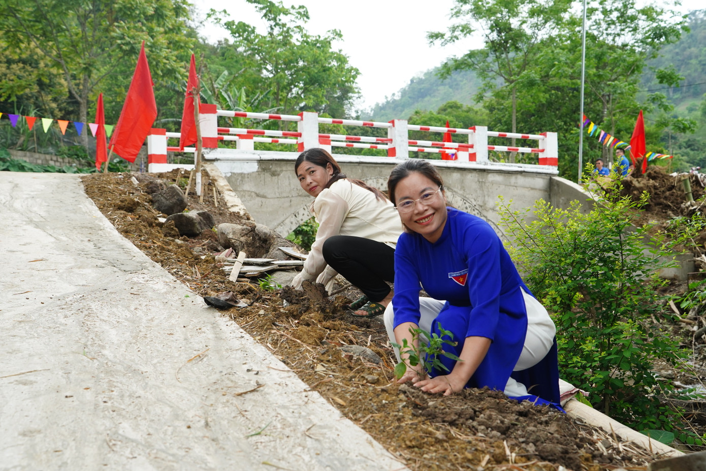 Các đại biểu, người dân cùng nhau trồng cây, tạo cảnh quan cho cây cầu.