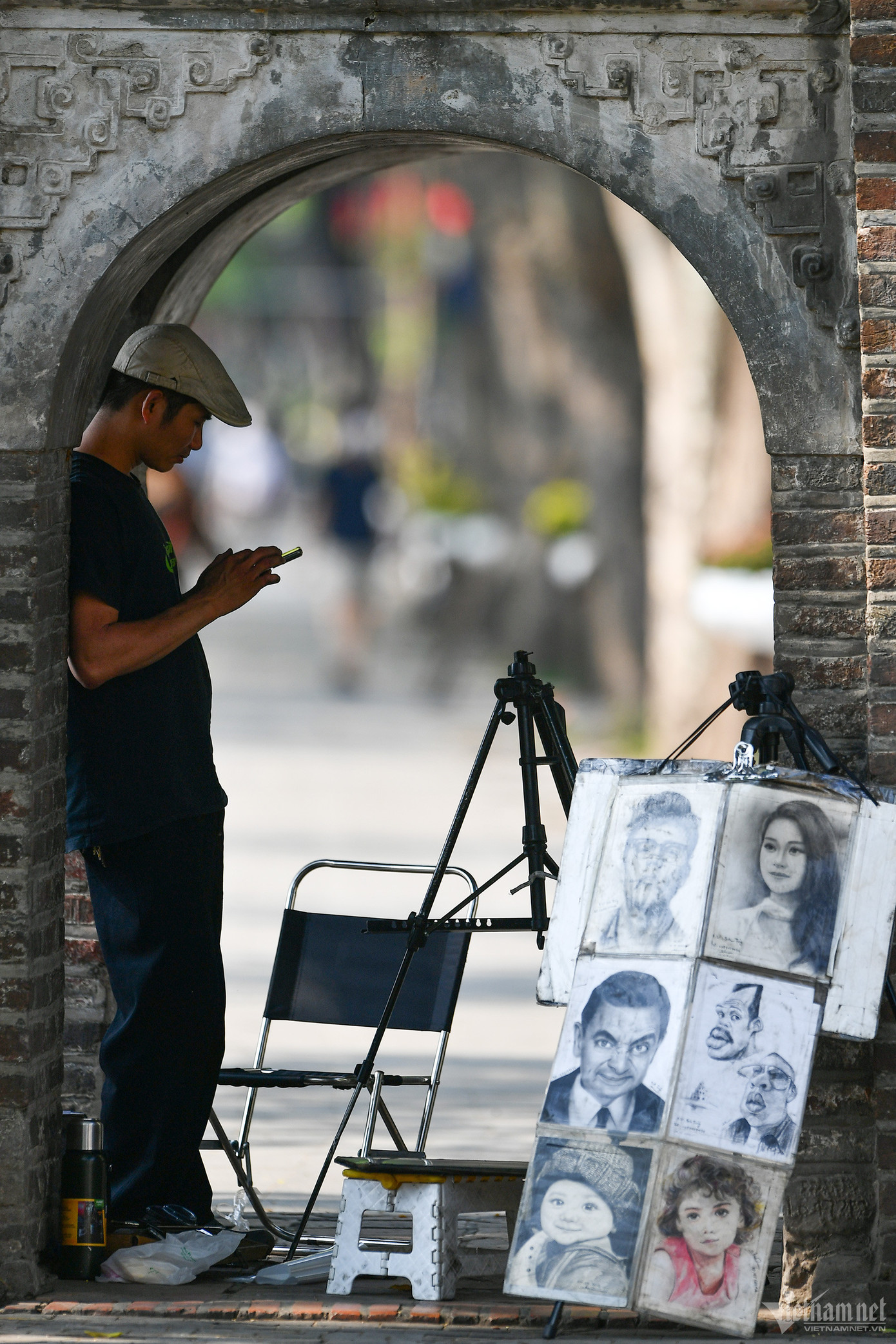 Một họa sĩ ký họa bên hồ Gươm kê đồ đứng trong tháp Hòa Phong để tránh nắng.