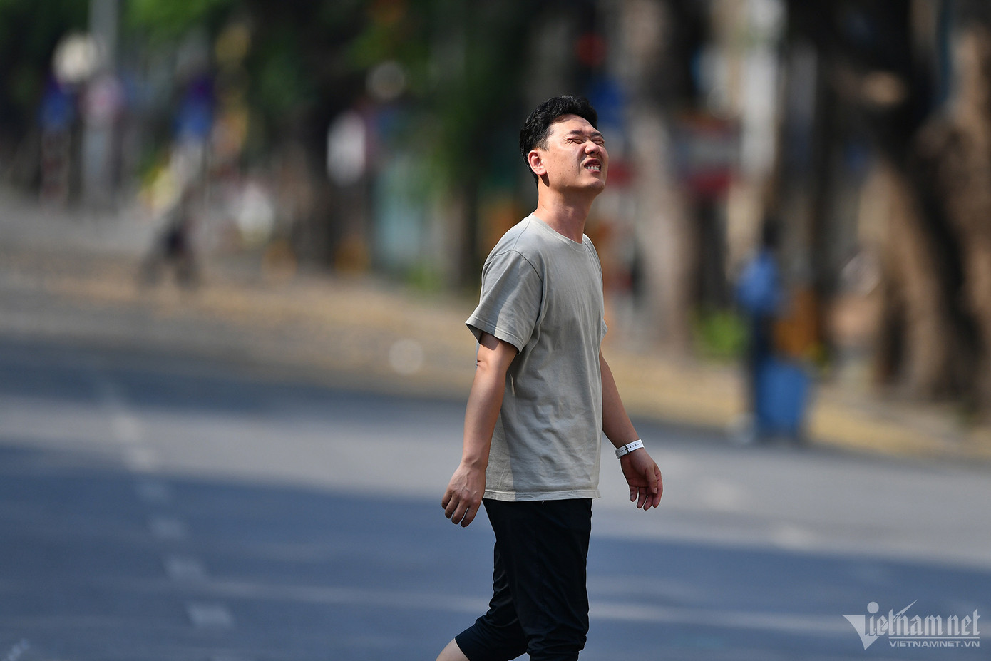Một thanh niên như muốn thở hắt ra khi đi ra khỏi bóng râm trên phố đi bộ.
