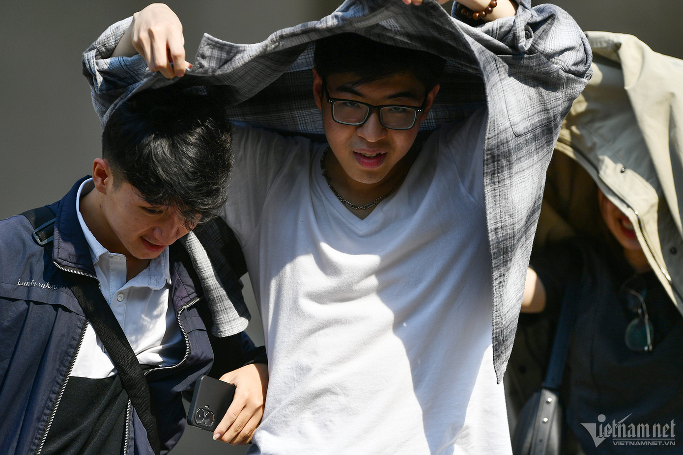 Nhóm nam thanh niên cũng phải tìm cách che chắn nắng khi vừa ra khỏi một cửa hàng trên phố Hàng Bài.