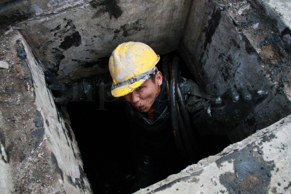 Anh Tuyến - một thành viên trong đội chui lên mặt đường sau cả buổi sáng làm việc dưới cống. Ảnh: Trường Phong