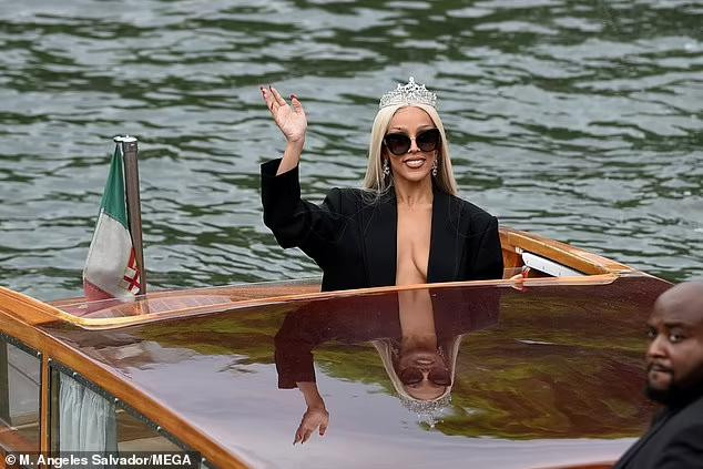 Nữ ca sĩ đình đám "thả rông" vòng một với áo blazer dài, đầu đội vương miện lấp lánh và đôi hoa tai cùng bộ, đi taxi dưới nước đến sự kiện.