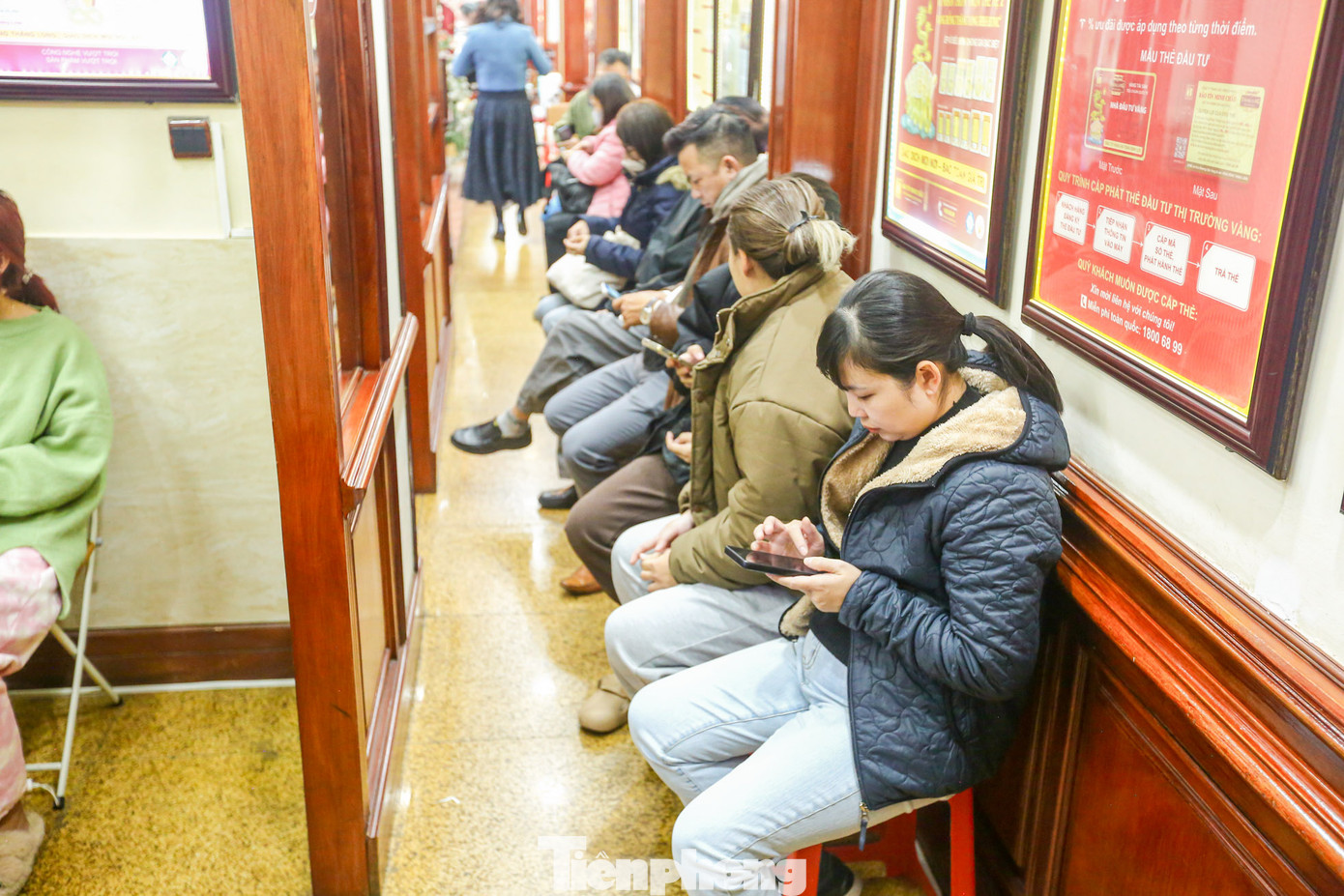 Người dân ngồi xếp hàng bên trong cửa hàng vàng.