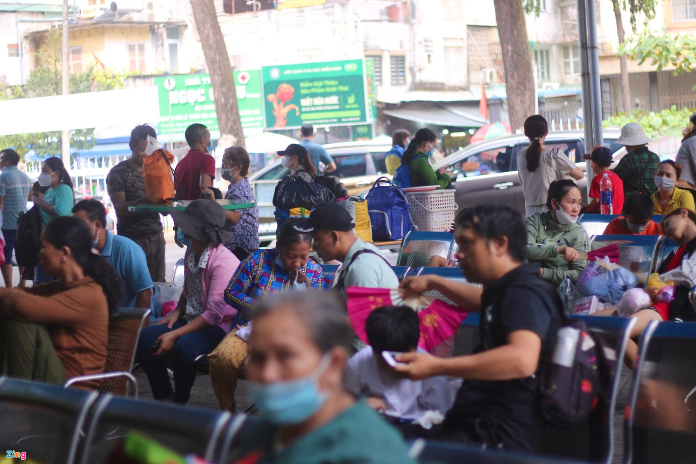 Trong thời tiết oi bức, mái che ở khu vực chờ làm thủ tục khám bệnh tại Bệnh viện Nhi đồng 2 nóng hầm hập. Nhiều người phải mua thêm quạt cho con. Ảnh: Bích Huệ.