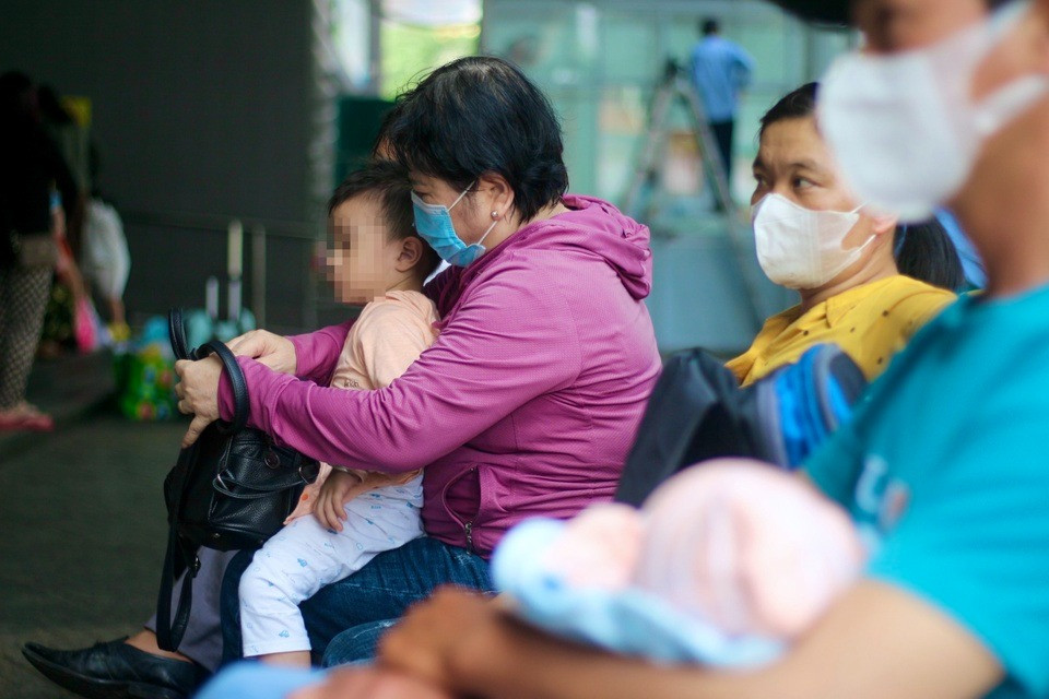 Bé trai ngồi chờ lượt khám cùng người thân trước sảnh Bệnh viện Nhi đồng 2. Ảnh: Bích Huệ.