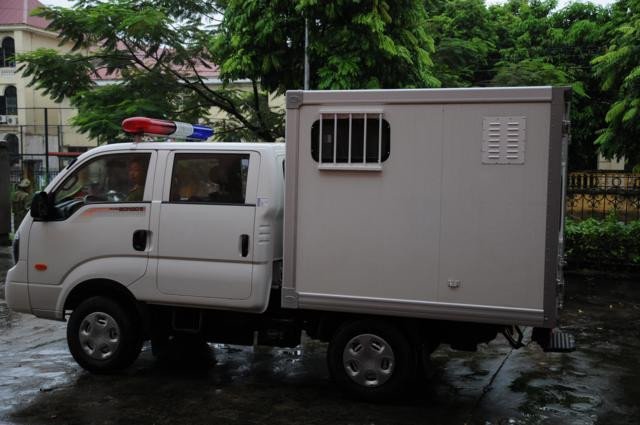 Chiếc xe chở phạm nhân từ từ tiến vào cổng tòa. Chiếc xe chở phạm nhân từ từ tiến vào cổng tòa