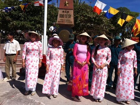 Biểu hiện sinh động nhất của chủ quyền và quyết tâm bảo vệ chủ quyền là các hộ dân sinh sống trên một số đảo của Trường Sa. Trong khi các ông chồng tham gia lực lượng dân quân tự vệ thì các bà vợ ký hợp đồng phục vụ trong các bếp ăn, hậu cần của các đơn vị bộ đội trên đảo. Con cái của họ học hết lớp 4 trên đảo sẽ vào đất liền để học lên tiếp. Trong ảnh: Các gia đình trên đảo Song Tử Tây tham gia đón khách cùng các chiến sĩ. Phía sau các bà vợ mặc áo dài rực rỡ là các ông chồng trong trang phục của dân quân, tự vệ đảo