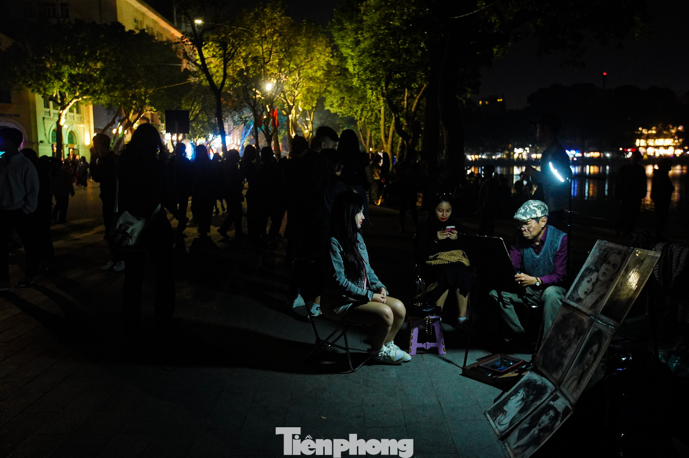 Dịch vụ vẽ chân dung quanh hồ Hoàn Kiếm vẫn diễn ra, các họa sĩ dùng ánh sáng từ đèn chiếu sáng nhỏ để tiếp tục công việc.