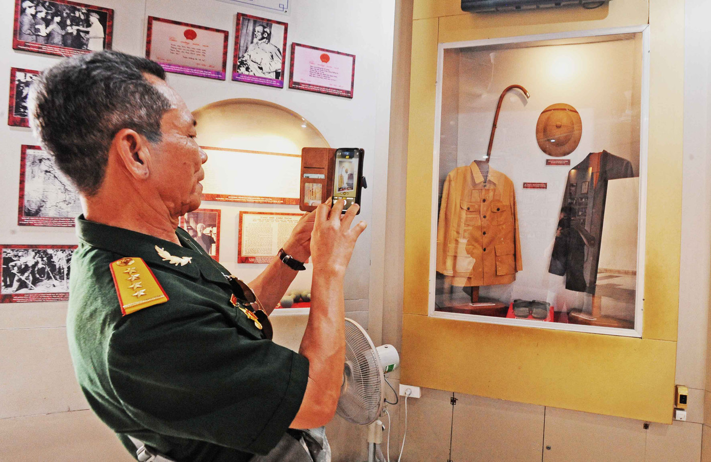 Một cựu chiến binh ở thành phố Việt Trì (Phú Thọ) chụp ảnh chiếc áo và mũ của Bác.