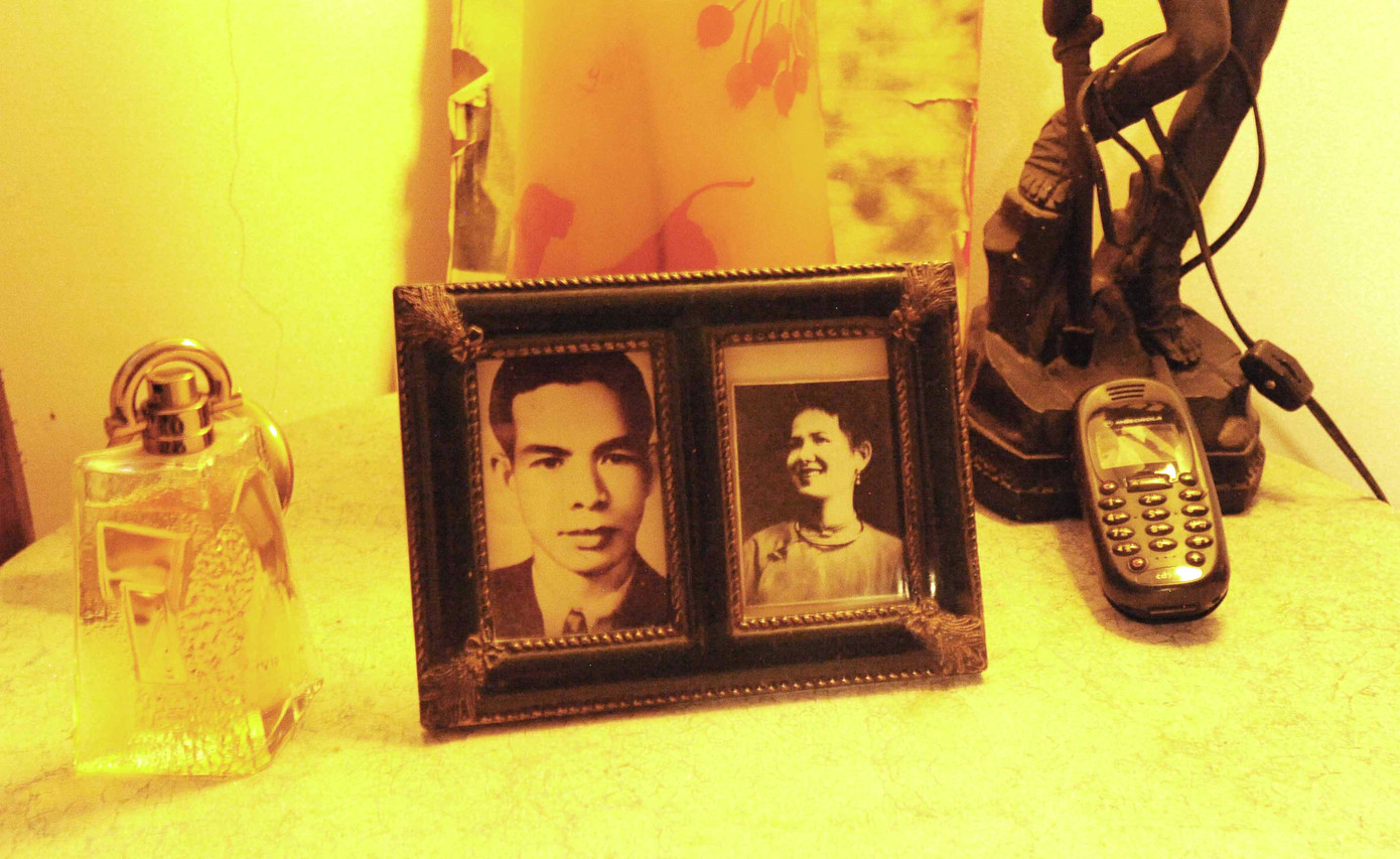 Trên đầu giường đặt hình ảnh ba mẹ và chiếc điện thoại chờ cuộc gọi của bạn bè. Trên đầu giường đặt hình ảnh ba mẹ và chiếc điện thoại chờ cuộc gọi của bạn bè.