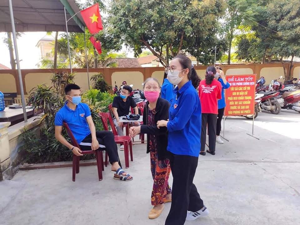 Nữ đoàn viên dìu cử tri lớn tuổi vào Hội trường bầu cử.