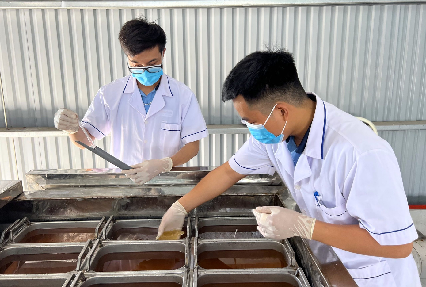 Các công nhân trong xưởng đang làm muối giảm mặn từ loại nước thải ra trong quá trình làm muối thủ công của bà con diêm dân.