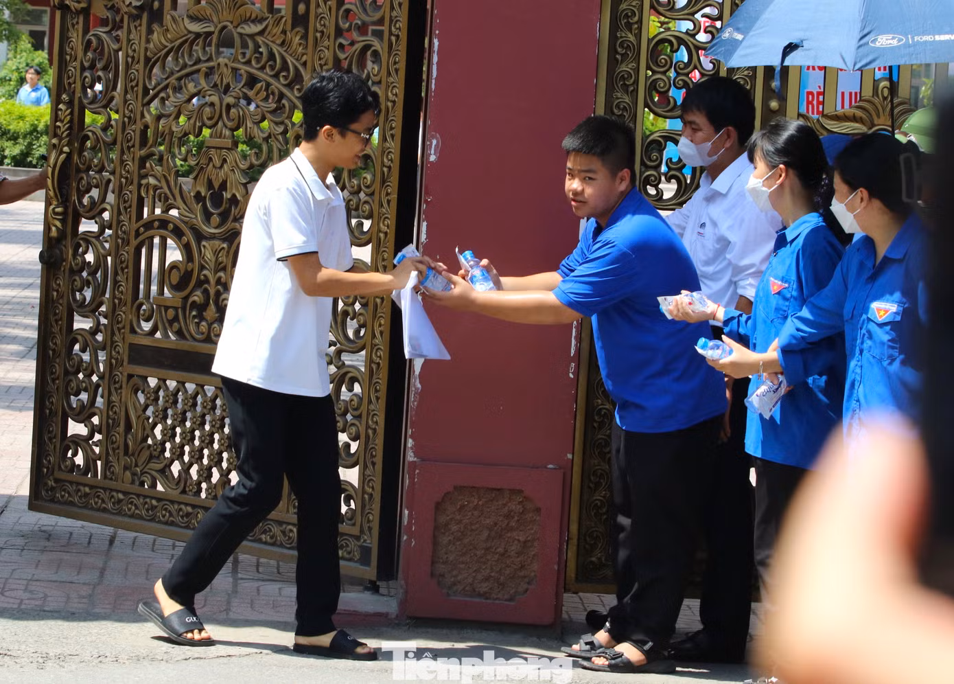 Tiếp nước cho thí sinh đầu tiên bước ra khỏi trường thi ở điểm thi THPT Huỳnh Thúc Kháng.